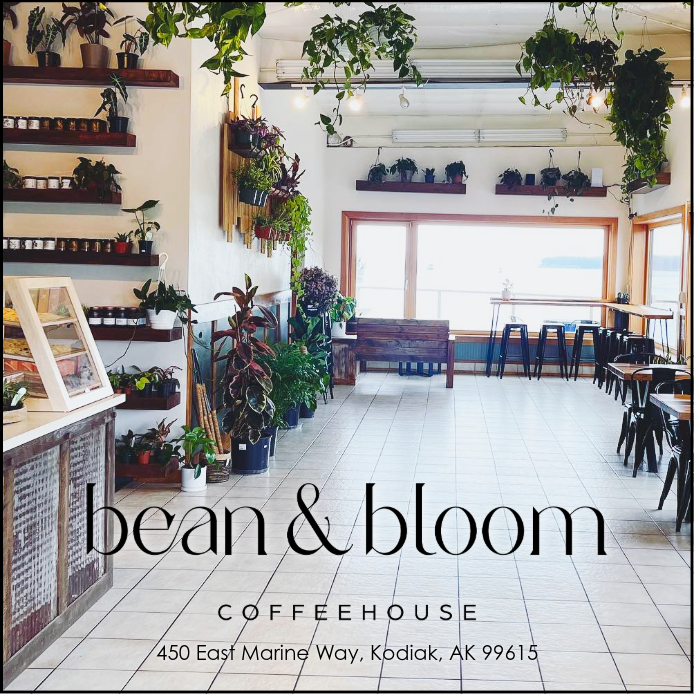 A bright, plant-filled coffeehouse with large windows, wooden tables and chairs, and shelves displaying potted plants—one of the best cafes in Kodiak. Text reads: bean bloom COFFEEHOUSE, 450 East Marine Way, Kodiak, AK 99615.